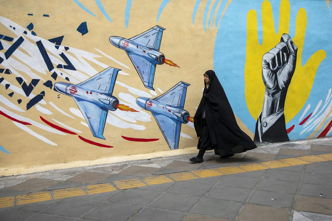  An Iranian woman passes in front of a pro-government political mural on April 12, 2026, in Tehran, Iran. Majid Saeedi/Getty Images 