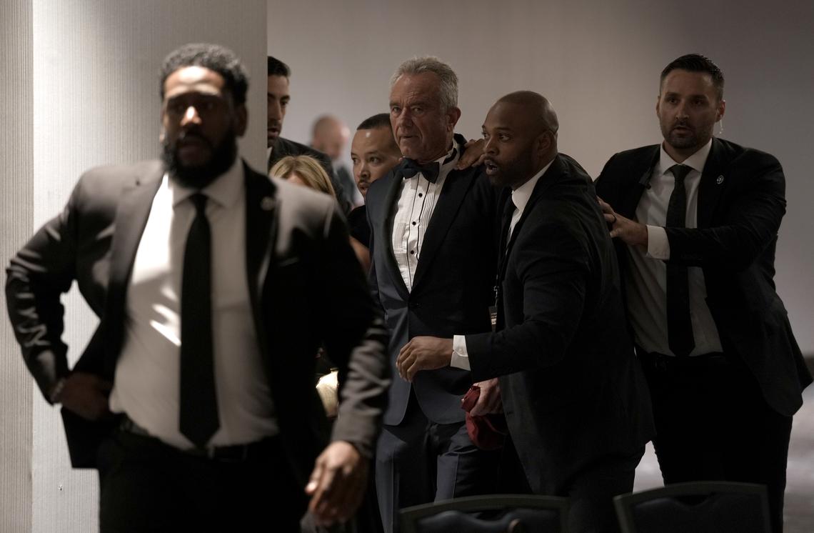Health Secretary Robert F. Kennedy Jr. and his wife Cheryl Hines, obscured, are rescorted out by security after shots were fired at the White House Correspondents' Association dinner in Washington on Saturday, April 25, 2026. President Donald Trump was rushed from the stage but appeared to be unharmed. (Salwan Georges/The New York Times)