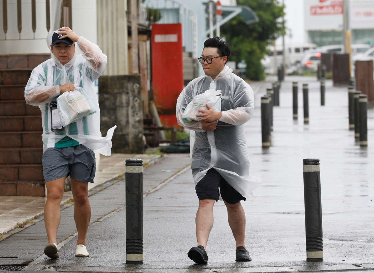 Pedestrians wearing raincoats make their way through strong winds as Typhoon Bavi approaches in Ishigaki, Japan, July 10, 2026. REUTERS/Kim Kyung-Hoon