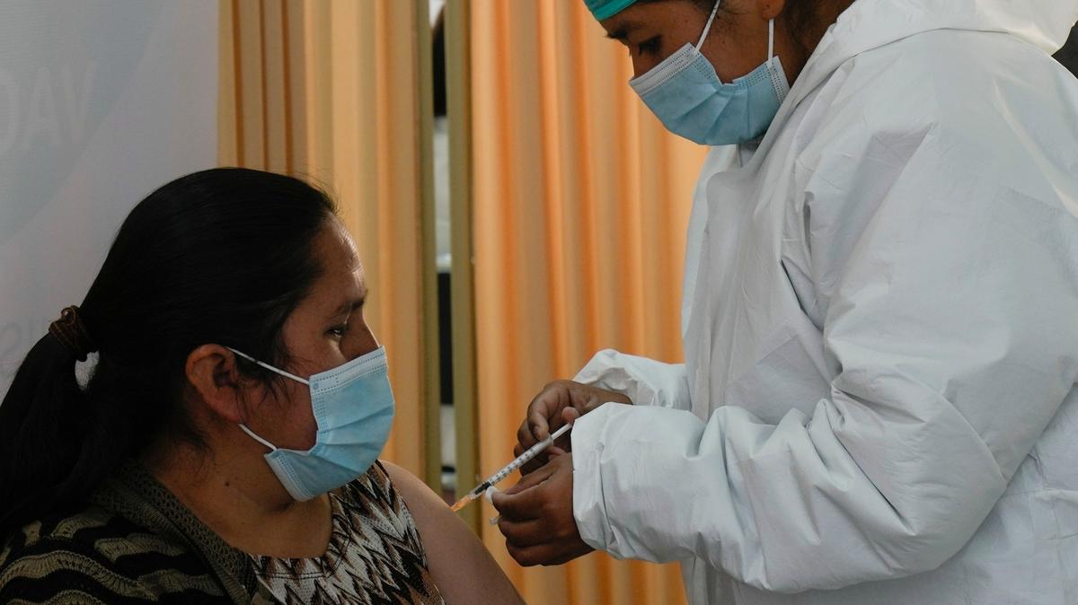 Personal médico vacuna a una mujer con el fármaco contra el COVID-19 Sputnik V en la Universidad Unifranz, durante una campaña para mayores de 30 años, en La Paz, Bolivia, el jueves 24 de junio de 2021. (AP Foto/Juan Karita)