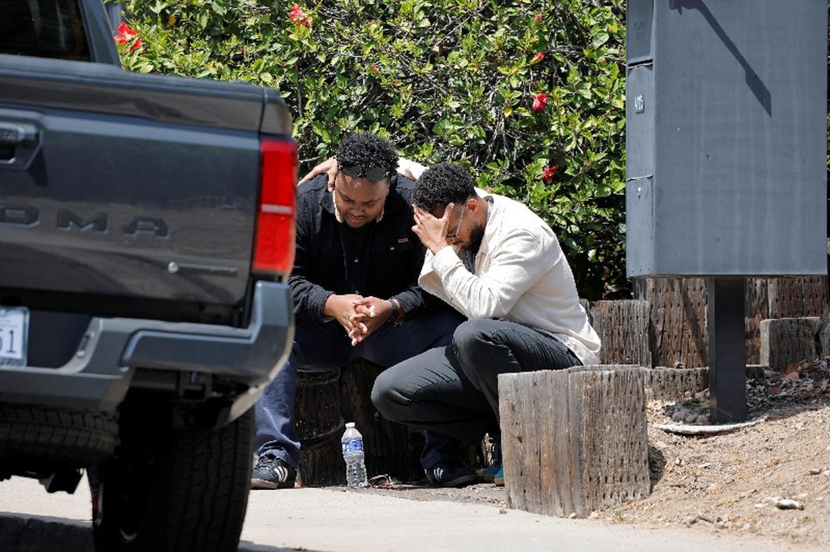 Men console each other as they sit on a sidewalk, near the scene of a reported active shooter situation at the Islamic Center, in San Diego, California, U.S., May 18, 2026.  REUTERS/Mike Blake
