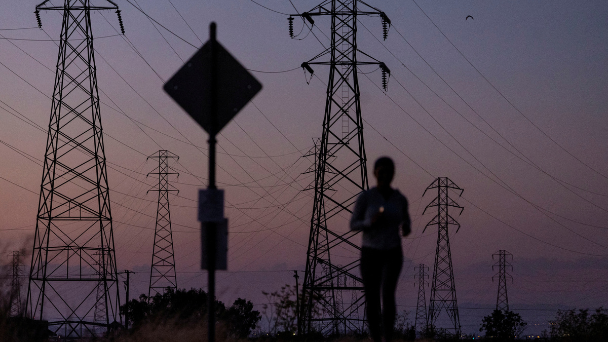 FILE PHOTO: A woman jogs by power lines, as California's grid operator urged the state's 40 million people to ratchet down the use of electricity in homes and businesses as a wave of extreme heat settled over much of the state, in Mountain View, California, U.S., August 17, 2022. REUTERS/Carlos Barria/File Photo