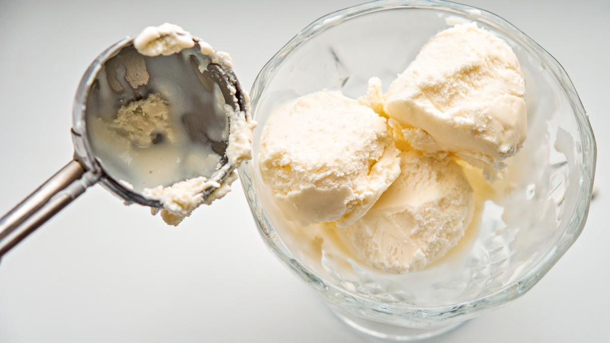 Scoops of ice cream in a glass jar and a dispenser-spoon for ice cream.