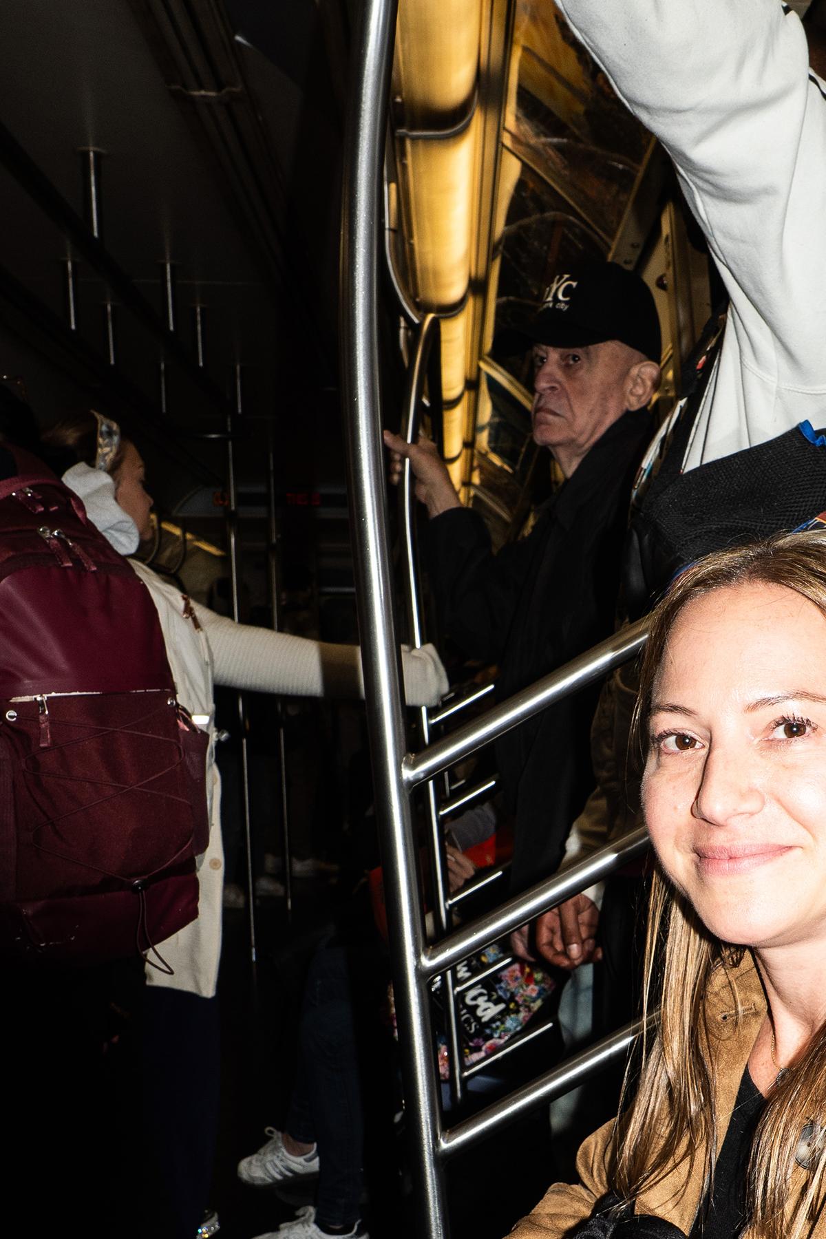 Rachel Behar, 37, an event planner, holds two iPhones while riding the L train in New York, May 11, 2026. Behar has one phone for work and one for everything else. (Graham Dickie/The New York Times)