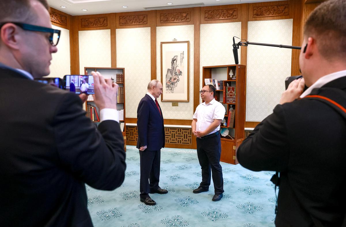 Russian President Vladimir Putin meets with Chinese engineer Peng Pai, who was photographed with him as a child 25 years ago during his first visit to China, at the Great Hall of the People in Beijing, China May 20, 2026. Sputnik/Vladimir Smirnov/Pool via REUTERS ATTENTION EDITORS - THIS IMAGE WAS PROVIDED BY A THIRD PARTY.