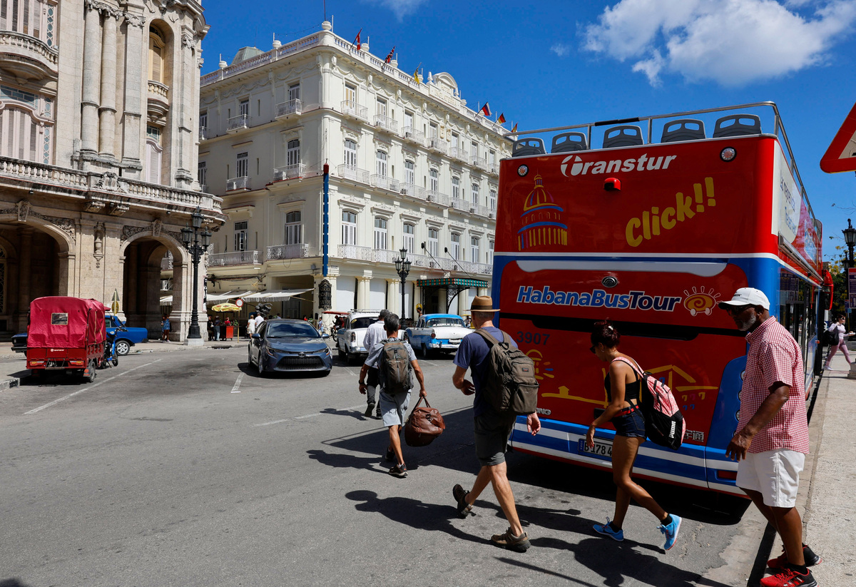Tourists cross a street near a hop-on hop-off sightseeing bus as U.S. sanctions have led most major tourism and travel companies to leave the island or drastically scale back their operations, in Havana, Cuba June 8, 2026. REUTERS/Norlys Perez
