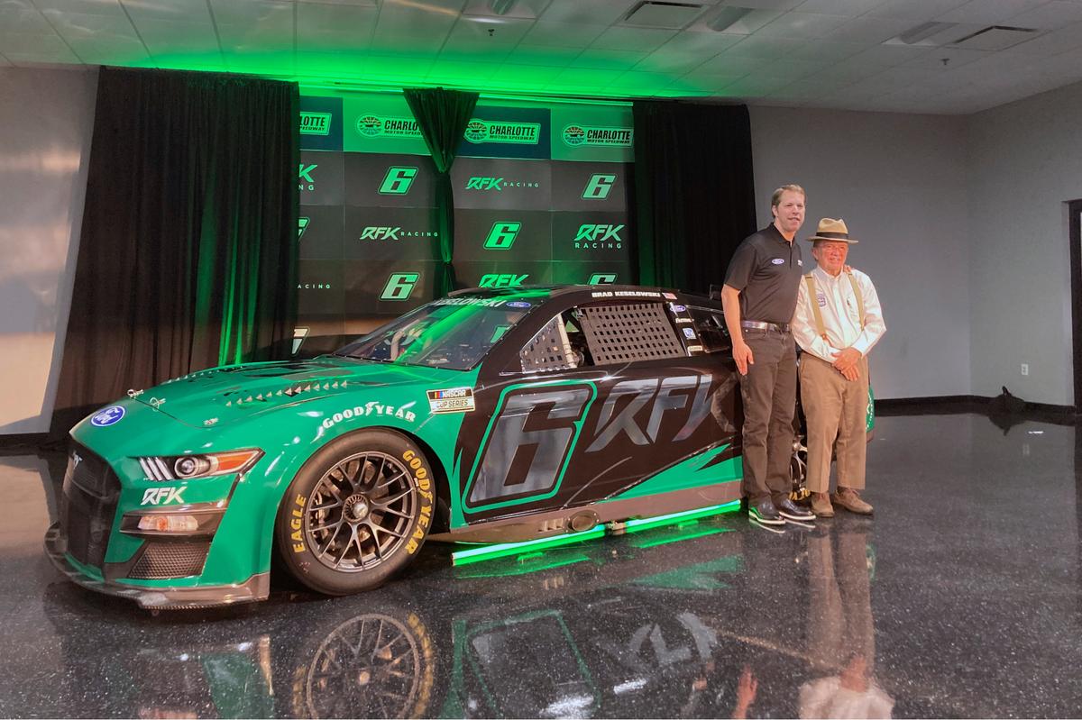 Brad Keselowski, left, stands next to Jack Roush in front of the No. 6 Ford that displays the new team name Roush Fenway Keselowski Racing, which will be called RFK Racing, on Tuesday, Nov. 16, 2021, at Charlotte Motor Speedway in Concord, N.C. (AP Photo/Jenna Fryer)