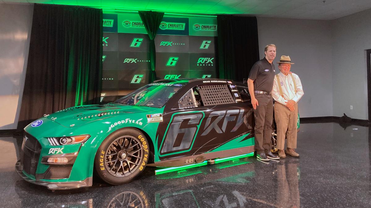 Brad Keselowski, left, stands next to Jack Roush in front of the No. 6 Ford that displays the new team name Roush Fenway Keselowski Racing, which will be called RFK Racing, on Tuesday, Nov. 16, 2021, at Charlotte Motor Speedway in Concord, N.C. (AP Photo/Jenna Fryer)