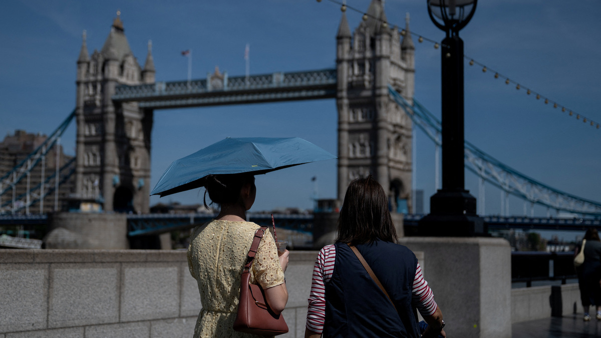 A woman uses an umbrella to shield herself from the sun near Tower Bridge in London, Britain May 22, 2026. REUTERS/Chris J. Ratcliffe/File Photo