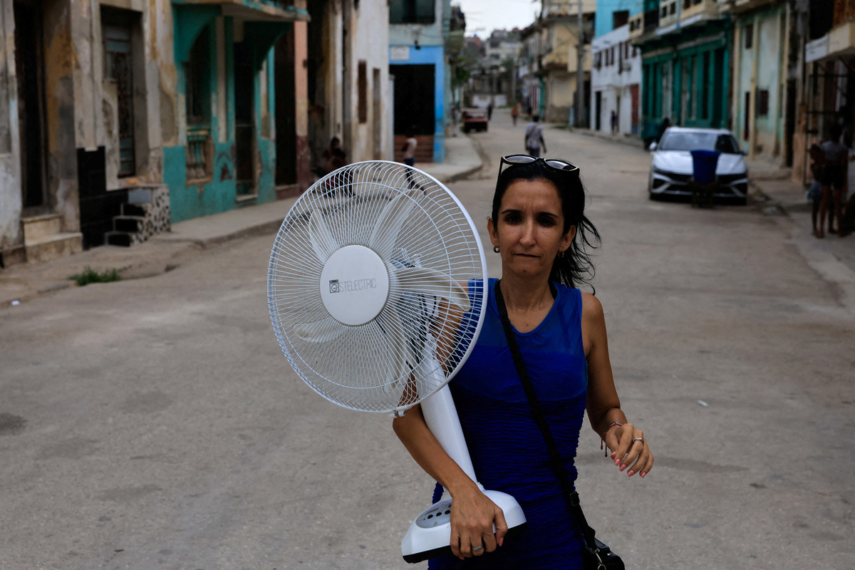 A woman walks on a street carrying a fan as Cuba's national electric grid collapsed at midday, leaving around 10 million people without power, in Havana, Cuba July 6, 2026. REUTERS/Norlys Perez
