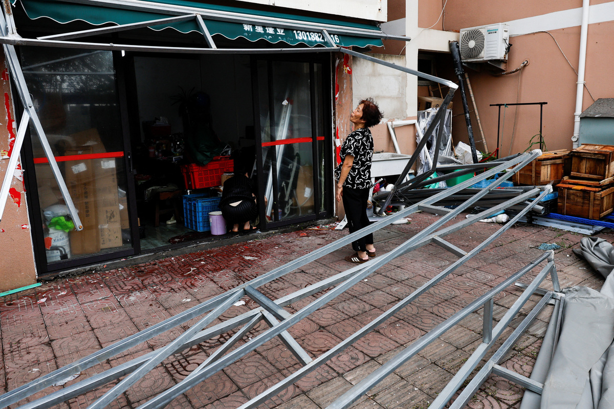 Ye Qiuyan, the owner of a store, looks at a damaged awning in the aftermath of Typhoon Bavi in the coastal village of Diaocaocun, Taizhou, Zhejiang province, China, July 12, 2026. REUTERS/Go Nakamura