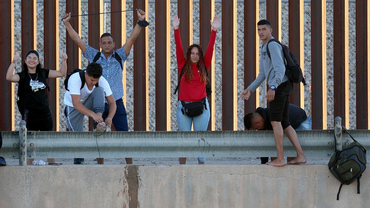 Venezuelan migrants gesture as they reach the U.S. border fence to turn themselves into the U.S. Border Patrol after crossing the Rio Grande from Mexico on Sept. 22, 2022, in El Paso, Texas.