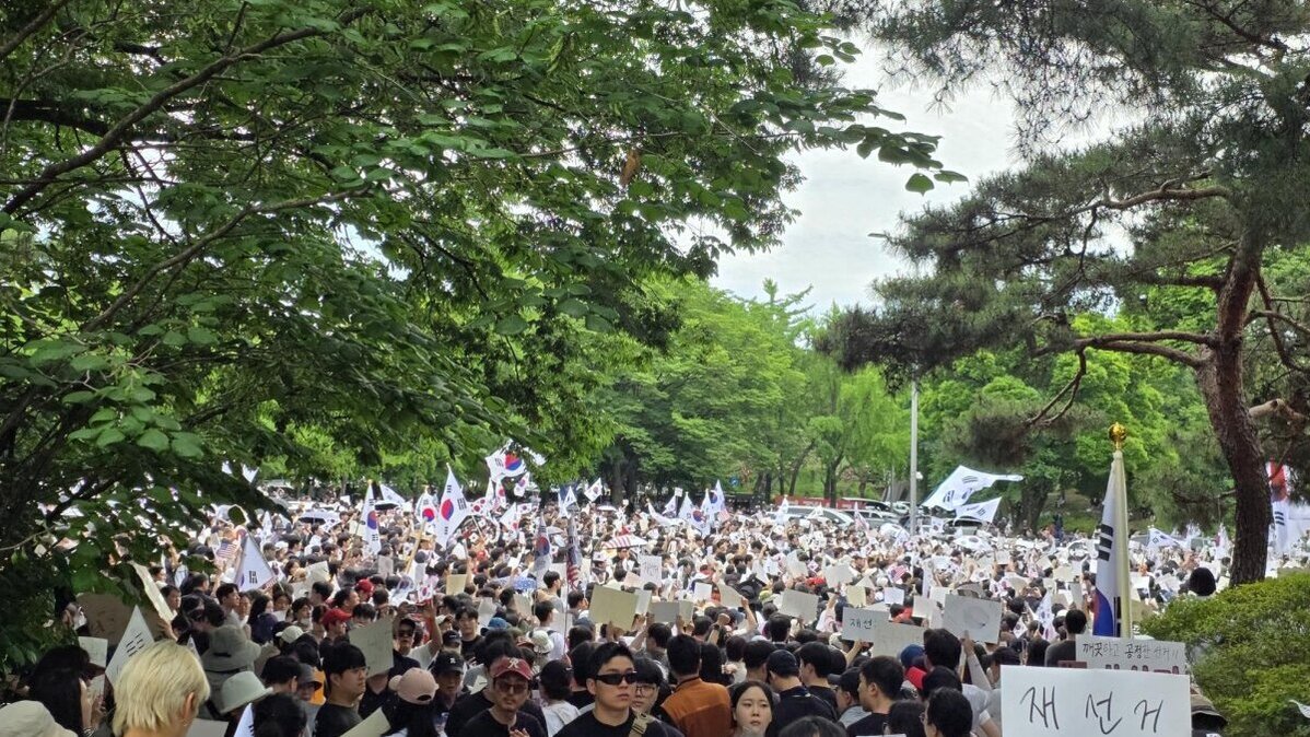 A crowd gathers outside Olympic Park Handball Gymnasium in Seoul’s Songpa District on Sunday to protest the election dispute, with participants waving South Korean flags and holding signs calling for a revote. Photo by Ju Byeong-gwan