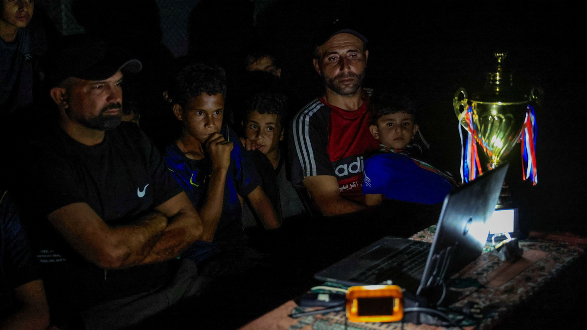 Former Palestinian soccer player Fadi Al-Arawi watches a 2026 World Cup match streamed on a laptop alongside others in Khan Younis, in the southern Gaza Strip, June 13, 2026. REUTERS/Haseeb Alwazeer