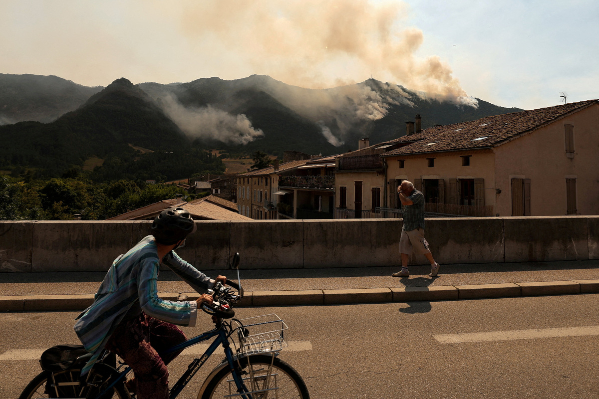 FILE PHOTO: People look at a wildfire which burns mountain vegetation for several days in Die in the Drome department during a heatwave affecting a large part of the country, France, July 9, 2026. REUTERS/Manon Cruz/File Photo