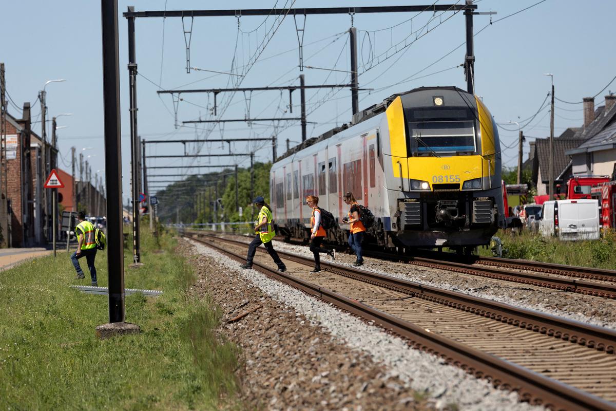 Emergency personnel walk near the scene where a school bus was struck by a train at a level crossing leading to multiple casualities, near the town of Buggenhout, Belgium, May 26, 2026. REUTERS/Bart Biesemans