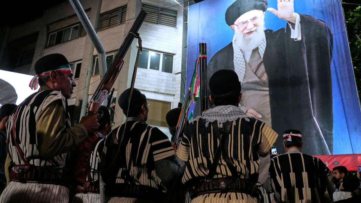 Iranians hold their guns during a pro-government gathering near the residence where former Iranian Supreme Leader Ayatollah Ali Khamenei was killed. AP Photo/Vahid Salemi. 