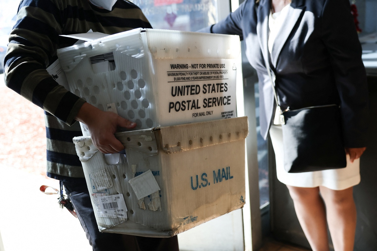  A customer carries packages to be shipped at the USPS Gardena Post Office in Gardena, California, on December 12, 2025. 