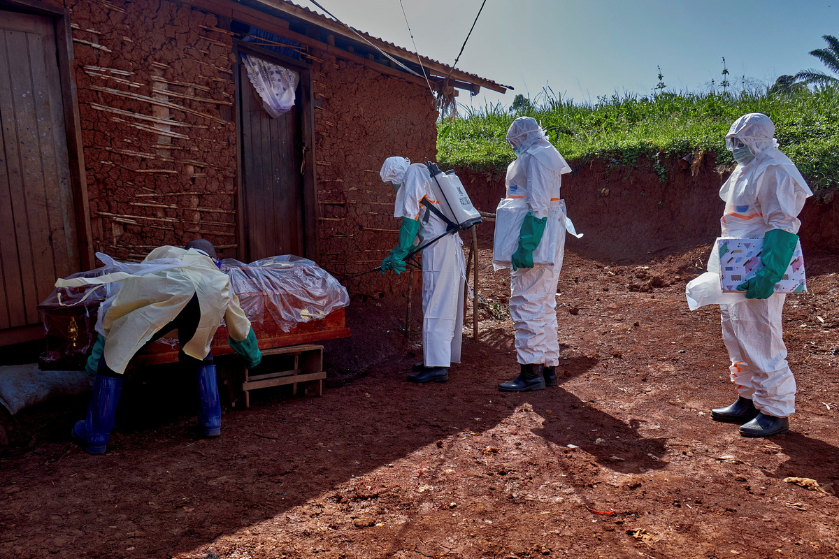 Red Cross workers wearing personal protective equipment (PPE) walk in a formation as they disinfect the house of an unidentified man who died of Ebola, before retrieving his body, as aid agencies intensify efforts to contain a new Ebola outbreak involving the Bundibugyo strain, in Quartier Shuni 1, a residential sector in Mongbwalu, Djugu Territory of Ituri province, Democratic Republic of the Congo, May 24, 2026. REUTERS/Gradel Muyisa Mumbere