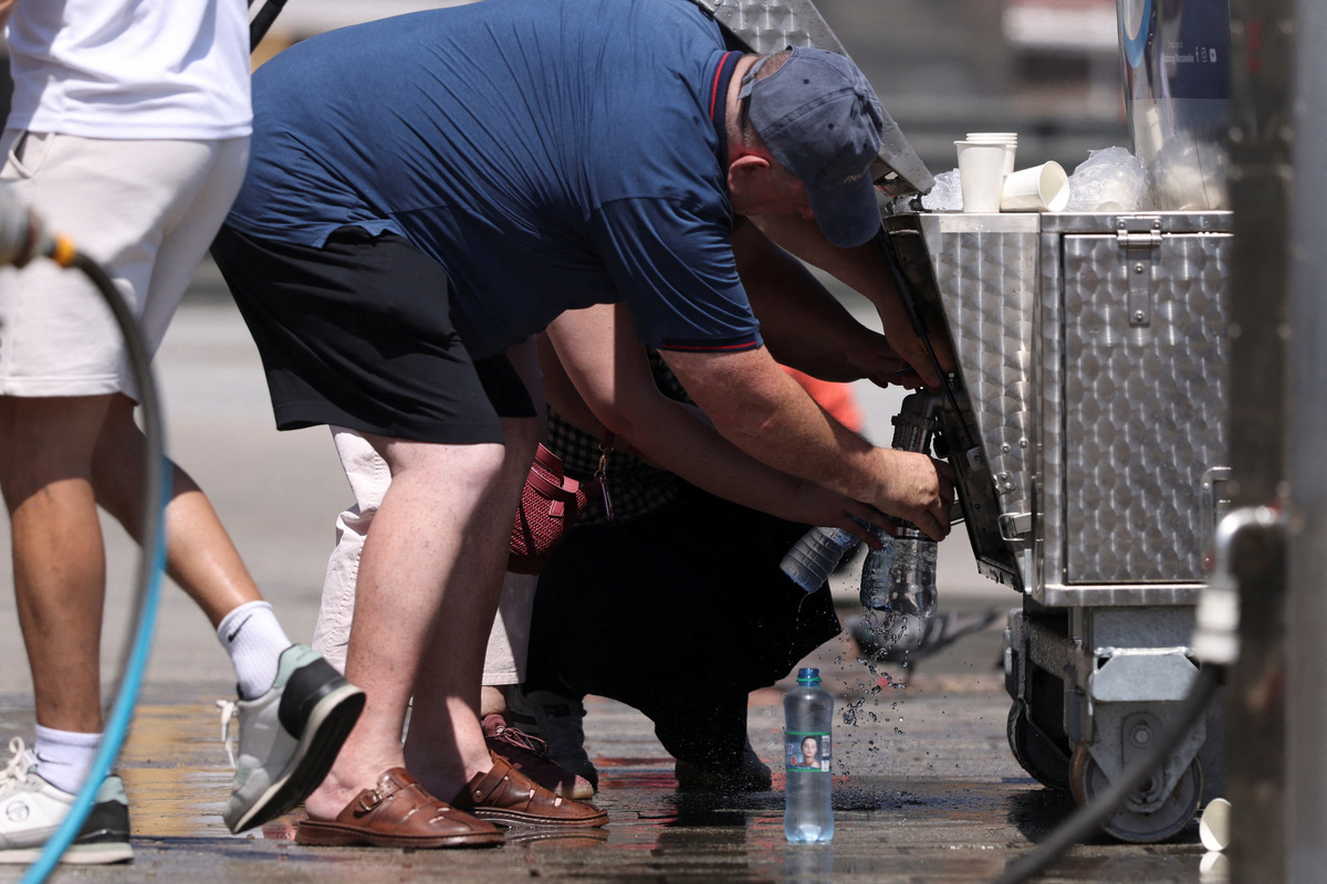 People fill bottles from a tanker providing free water, set up by the city due to the heatwave, in Warsaw, Poland, June 28, 2026. REUTERS/Kuba Stezycki