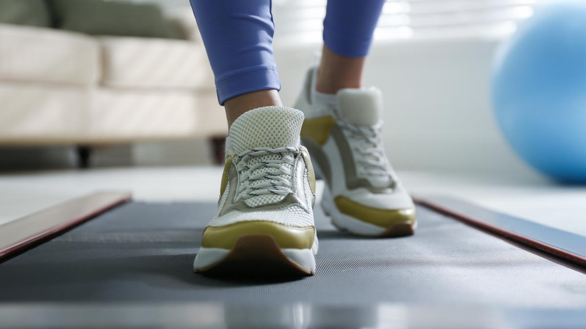 Woman training on walking treadmill at home, closeup