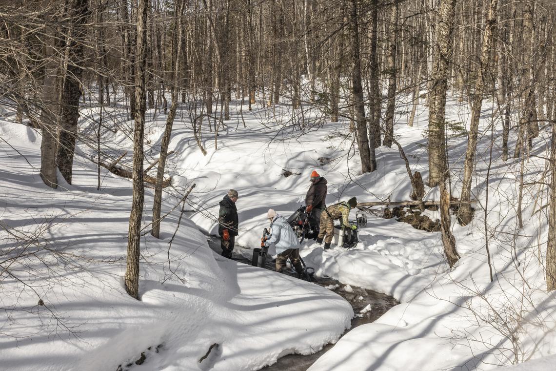 A team packs materials into the Avon Valley Brook tributary off the Sandy River in Farmington, Maine, March 3, 2026. The fragile hope for salmon recovery in Maine: a long-term project to remove or modify dams may clear the way for endangered wild Atlantic salmon to swim freely up to the Sandy River, but it faces opposition from business and lawmakers. (Greta Rybus/The New York Times)