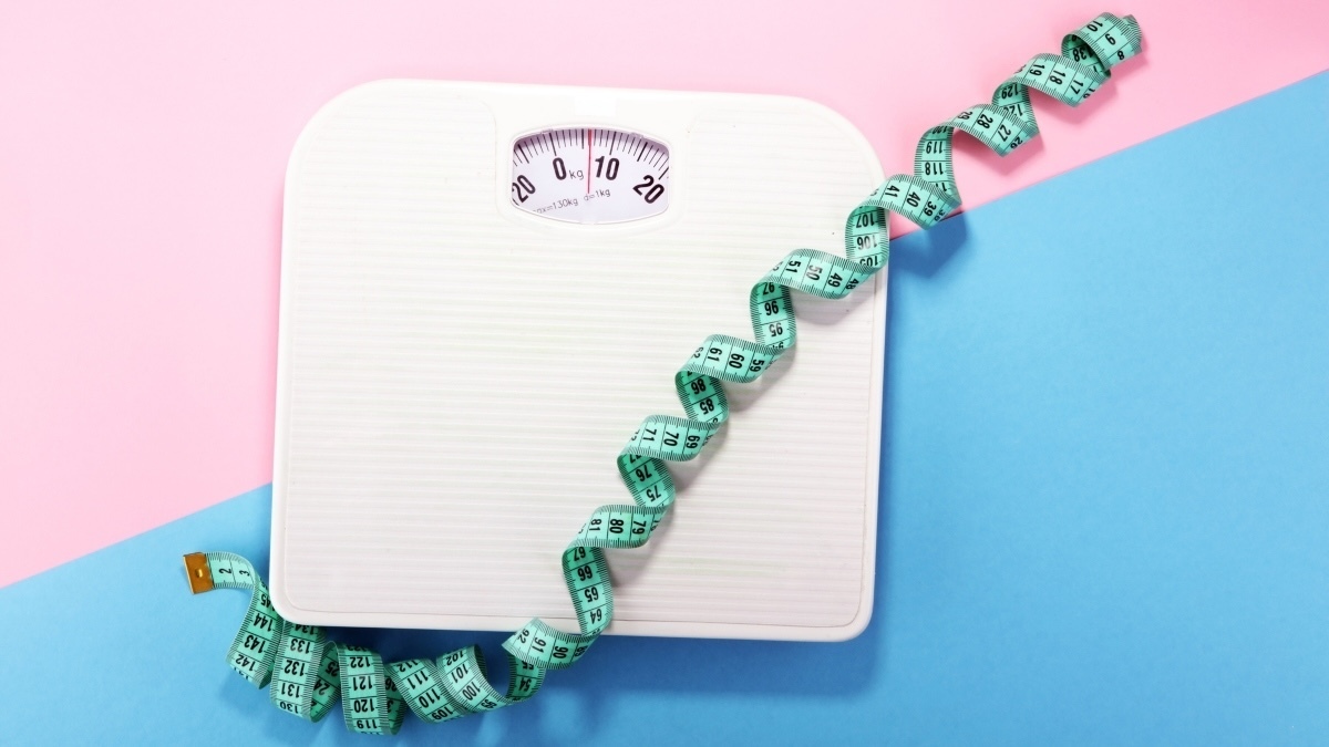 weight and tape measure and concept of diet and healthy lifestyle flat lay on colored paper