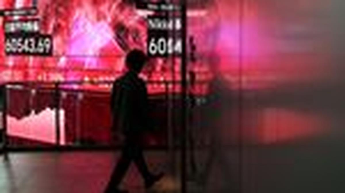 A man walks in front of an electronic screen displaying Japan's Nikkei share average inside a conference hall in Tokyo, Japan, April 27, 2026. REUTERS/Issei Kato