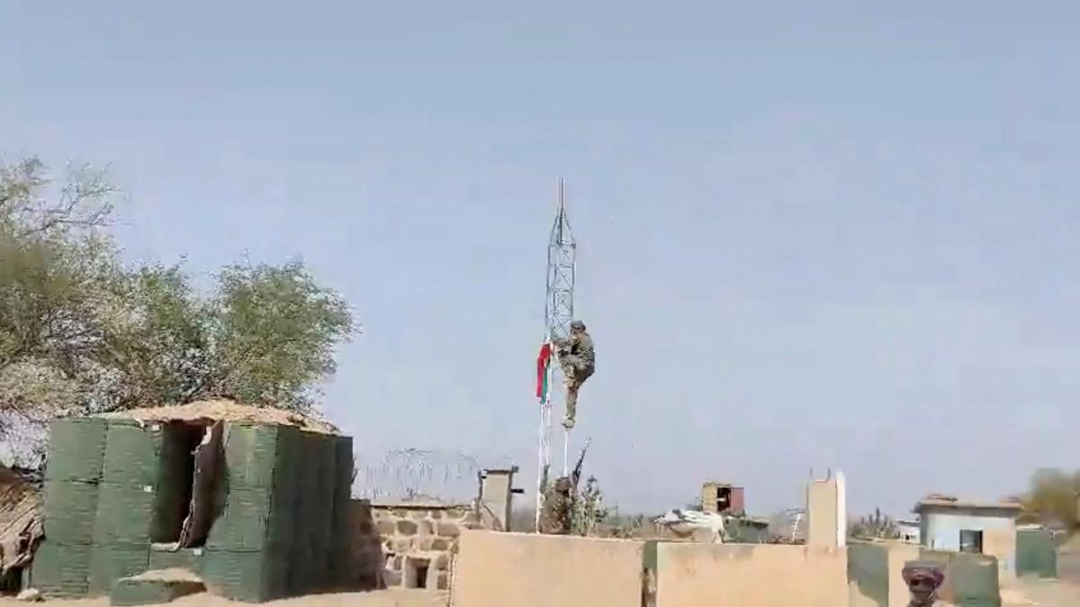 A militant climbs up a tower with a flag at at what appears to be a military base with barricades and makeshift container buildings, in Tessalit, Mali, in this screen grab obtained from a social media video released on May 1, 2026. SOCIAL MEDIA/via REUTERS