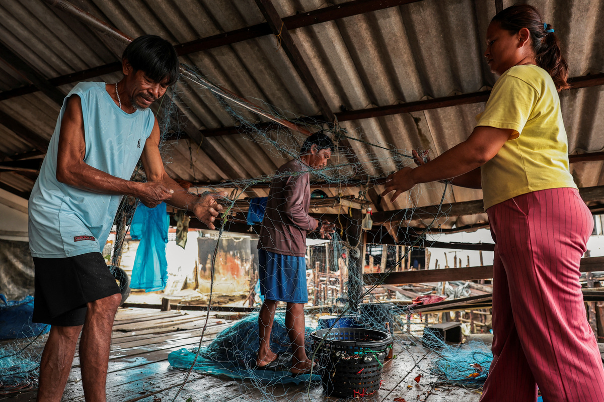 Chaiyaporn Arunrasamee, 50, a local fisherman, works on a fishing net with his relatives on Koh Haad Sai Dam Island, in Ranong province, Thailand, May 20, 2026. REUTERS/Chalinee Thirasupa