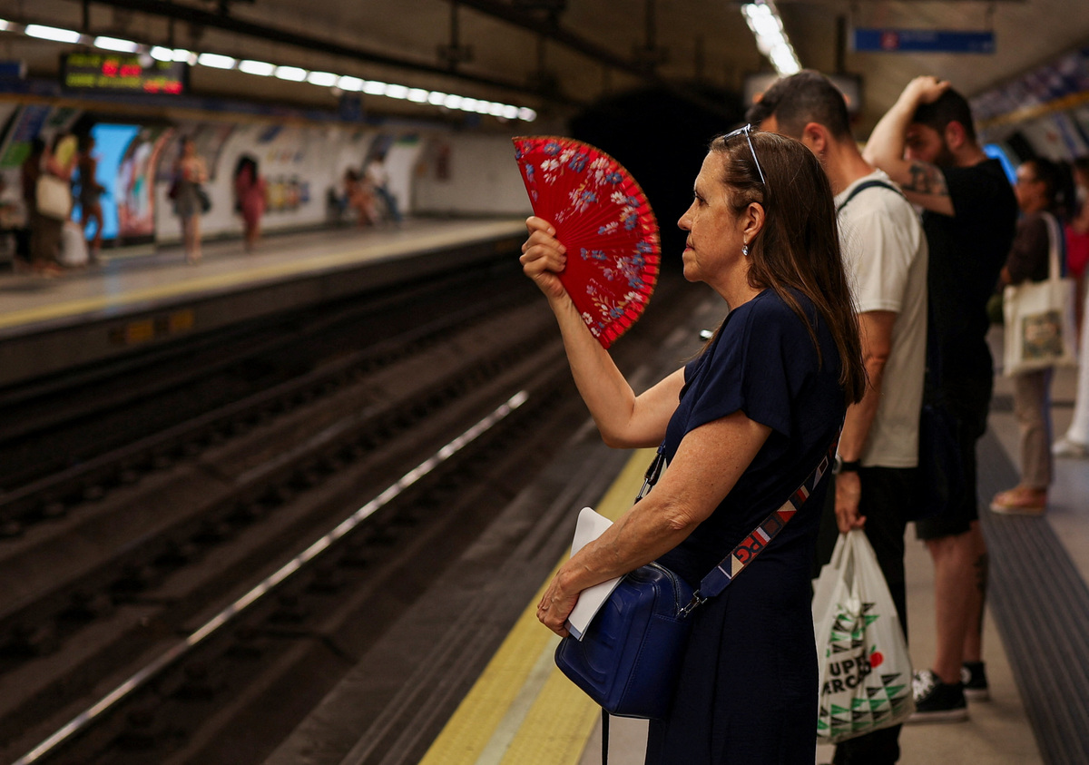 A woman uses a fan, as commuters wait to board a metro on a hot day in Madrid, Spain June 21, 2026. REUTERS/Mohammed Salem