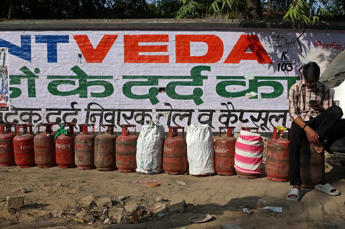 A man uses his phone as he waits to get his LPG gas cylinder refilled outside a gas agency Kanpur, India, May 14, 2026. REUTERS/Bhawika Chhabra