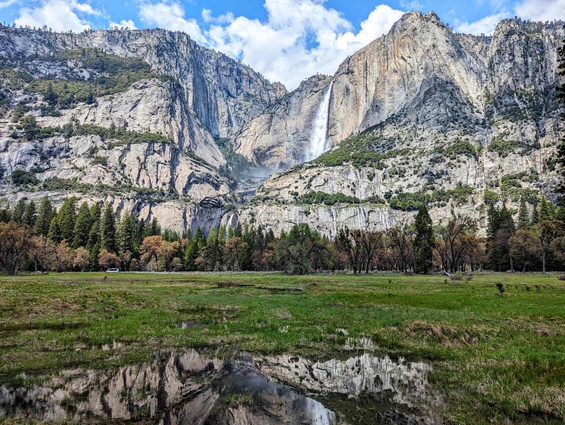 Yosemite Falls, and its reflection in a puddle of water in the meadow below, is seen on April 23, 2024, at Yosemite National Park.