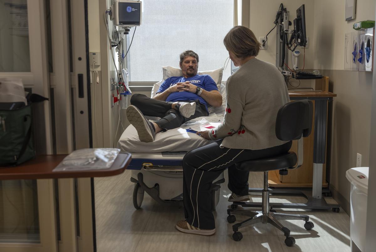 Rickey Malloy, who was diagnosed with ALS in July 2023, with the nurse Kelly McCoy Gross, after receiving an infusion in St. Louis, on Jan. 27, 2026. The drug, tofersen, made by Biogen and marketed as Qalsody, is for a small subset of patients. But evidence that breathing and strength can get better for some of them is remarkable for a paralyzing, usually fatal disease. (Julia Rendleman/The New York Times)