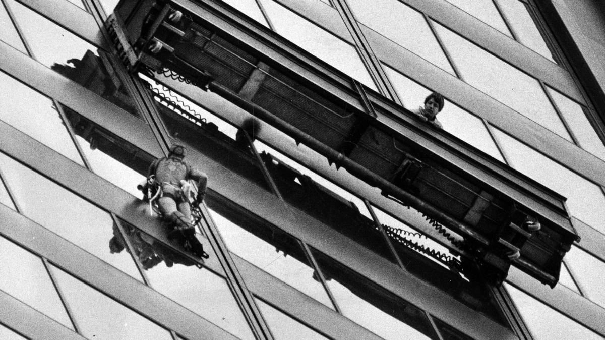 Dan Goodwin makes his way up the Sears Tower on May 25, 1981, as would-be rescuers lowered on scaffolding. But the 25-year-old daredevil just rushed by them and waved on his way to the top of the giant building, the worlds tallest. (Walter Kale/Chicago Tribune/TNS)