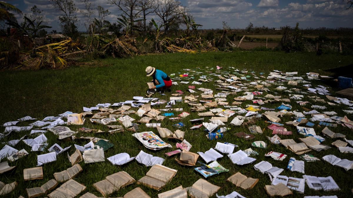 Una maestra seca libros al sol en una escuela muy perjudicada por el paso del huracán Ian por La Coloma, en la provincia de Pinar del Río, Cuba, el 5 de octubre de 2022. (AP Foto/Ramón Espinosa)