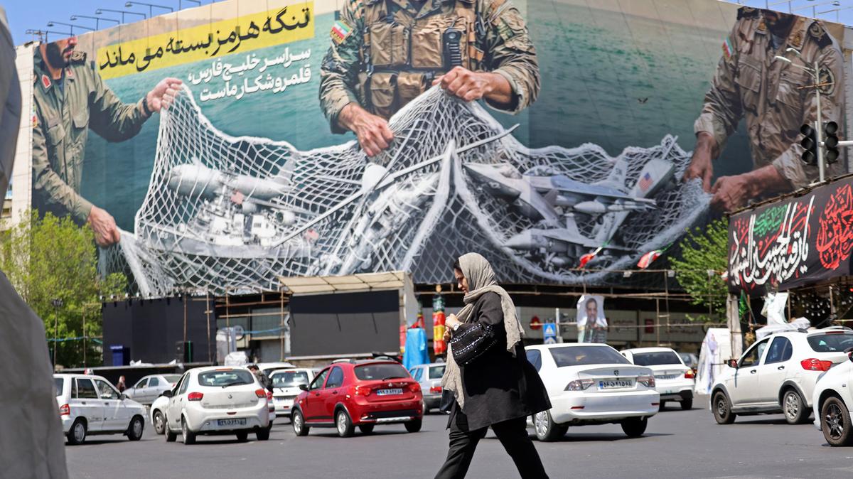 A woman walks past a giant billboard reading "The Strait of Hormuz remains closed" at the Revolution Square in Tehran, Iran, on April 12, 2026. (Atta Kenare/AFP/Getty Images/TNS)