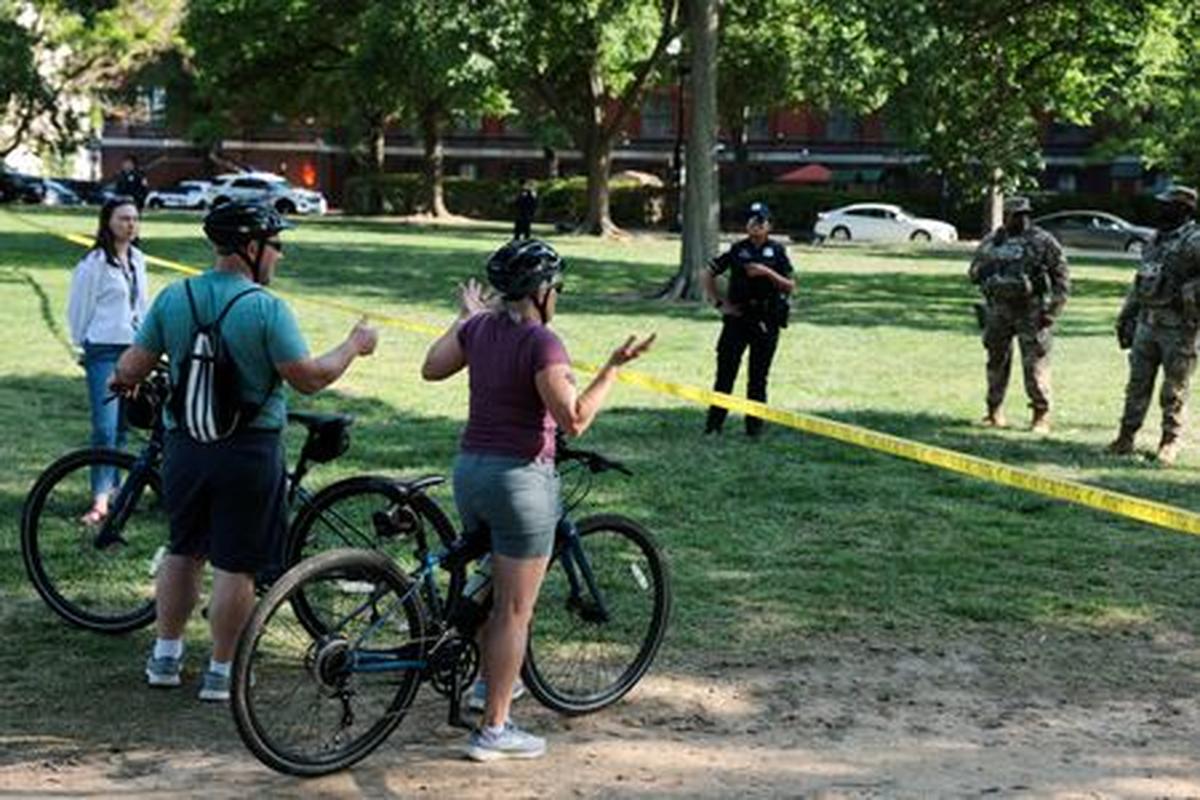 Tourists talk to law enforcement officers as they stand watch behind a cordon off area at the scene of an officer-involved shooting, with the Washington Monument in the background, in Washington, D.C., U.S., May 4, 2026. REUTERS/Jonathan Ernst
