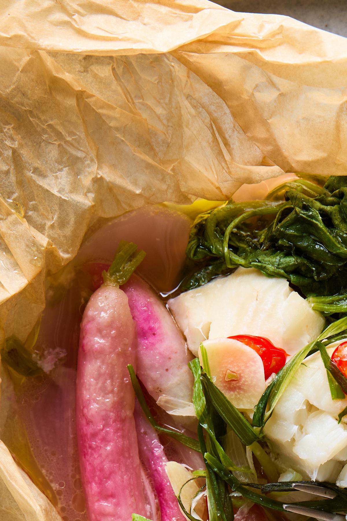 Parchment-steamed fish with buttered radishes. Aromatic parcels of spoon-tender white fish fillets, sweet steamed radishes and peppery greens are a delight to unwrap. Food styled by Brett Regot. (Ghazalle Badiozamani/The New York Times)