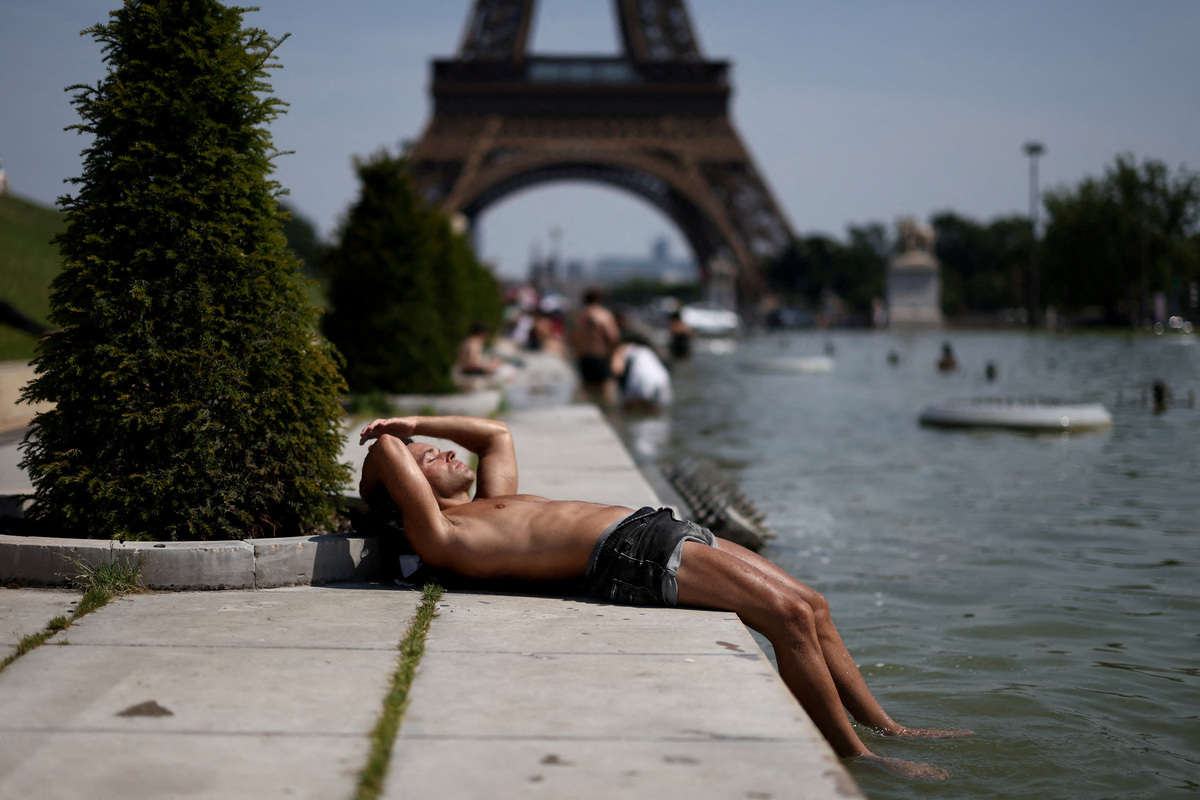 FILE PHOTO: A person sunbathes next to the Trocadero Fountains by the Eiffel Tower during high temperatures amid a heatwave in Paris, France, June 27, 2026. REUTERS/Tom Nicholson/File Photo