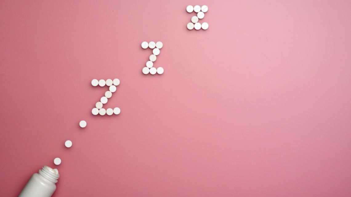 Pills or tablets for slipping. Bottle with soporific pills on pink background.