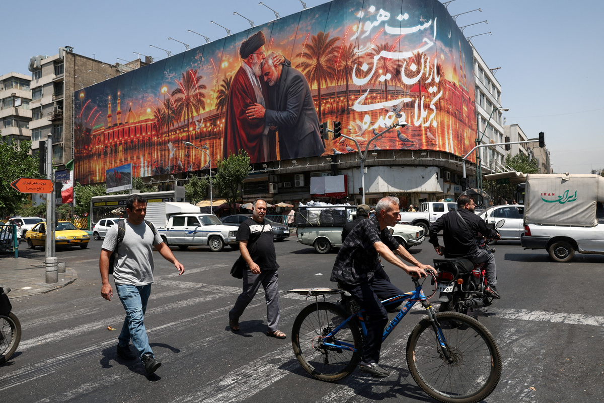 FILE PHOTO: People move past a billboard with an image which depicts Iran's late Supreme Leader Ayatollah Ali Khamenei embracing late senior Iranian military commander General Qassem Soleimani, in Tehran, Iran, June 28, 2026. Majid Asgaripour/WANA (West Asia News Agency) via REUTERS./File Photo