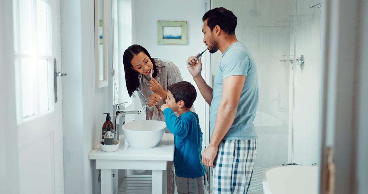  A stock image of parents, child and brushing teeth in family home bathroom while learning or teaching dental hygiene. 