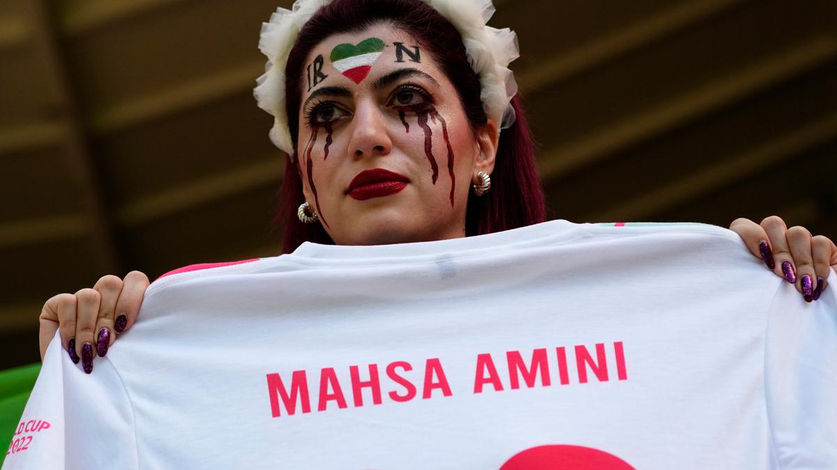 Una mujer sostiene una camiseta con el nombre de Mahsa Amini, una mujer que murió mientras estaba bajo custodia policial en Irán a la edad de 22 años, mientras toma su lugar en las gradas antes del partido de fútbol del grupo B de la Copa Mundial entre Gales e Irán, en el estadio Ahmad Bin Ali en Al Rayyan, Catar, el viernes 25 de noviembre de 2022. (Foto AP/Pavel Golovkin)
