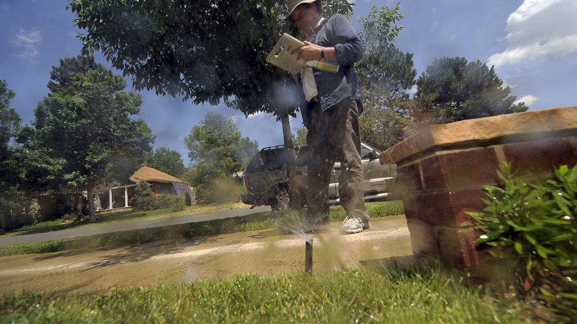 Denver Water Saver Edward Kosinski writes up a report on a property in Denver where a sprinkler was watering the lawn late in the afternoon on July 10, 2012. The property owner was given a warning because of the amount of water running down the gutter. (John Leyba/The Denver Post/TNS)