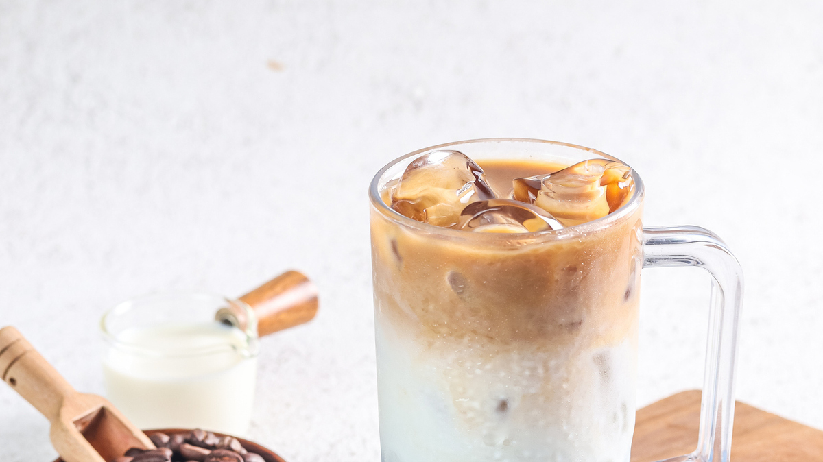 blueberry milk coffee with some coffee beans and placed on a wooden plate