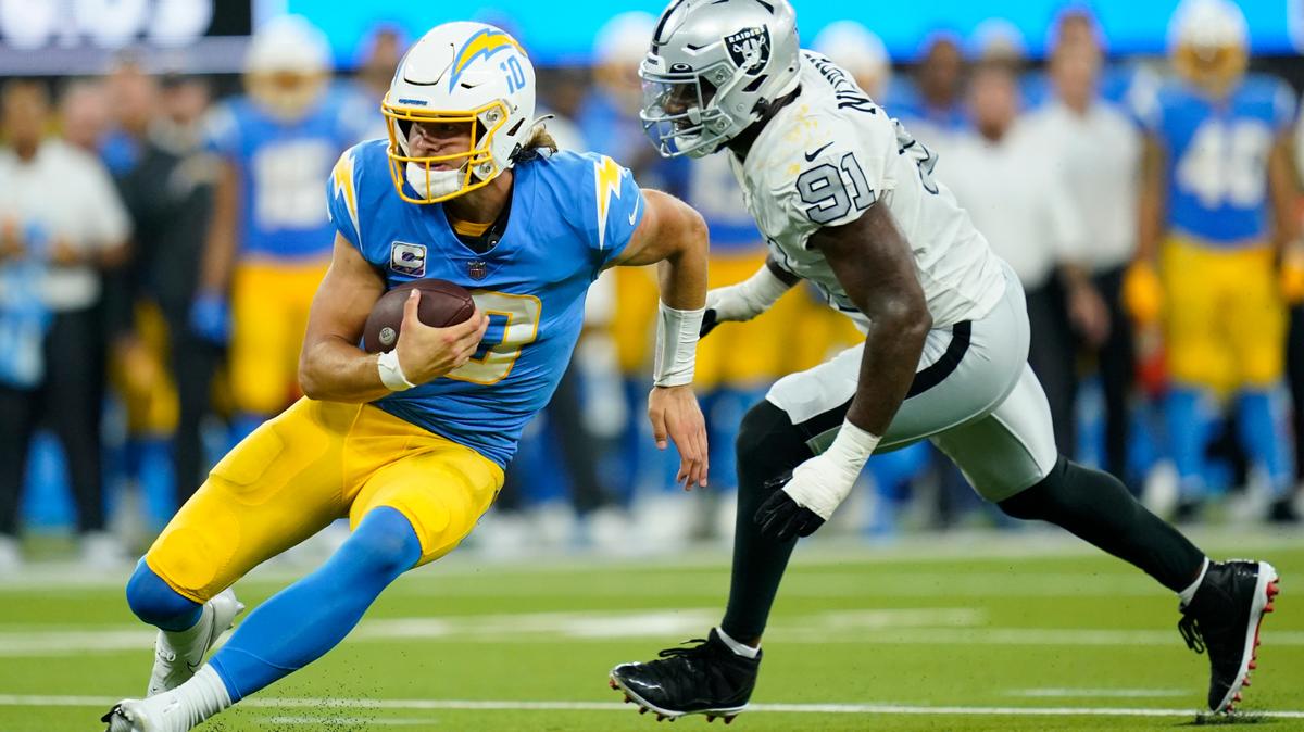 Los Angeles Chargers quarterback Justin Herbert runs with the ball as Las Vegas Raiders defensive end Yannick Ngakoue defends during the second half of an NFL football game Monday, Oct. 4, 2021, in Inglewood, Calif. (AP Photo/Ashley Landis)