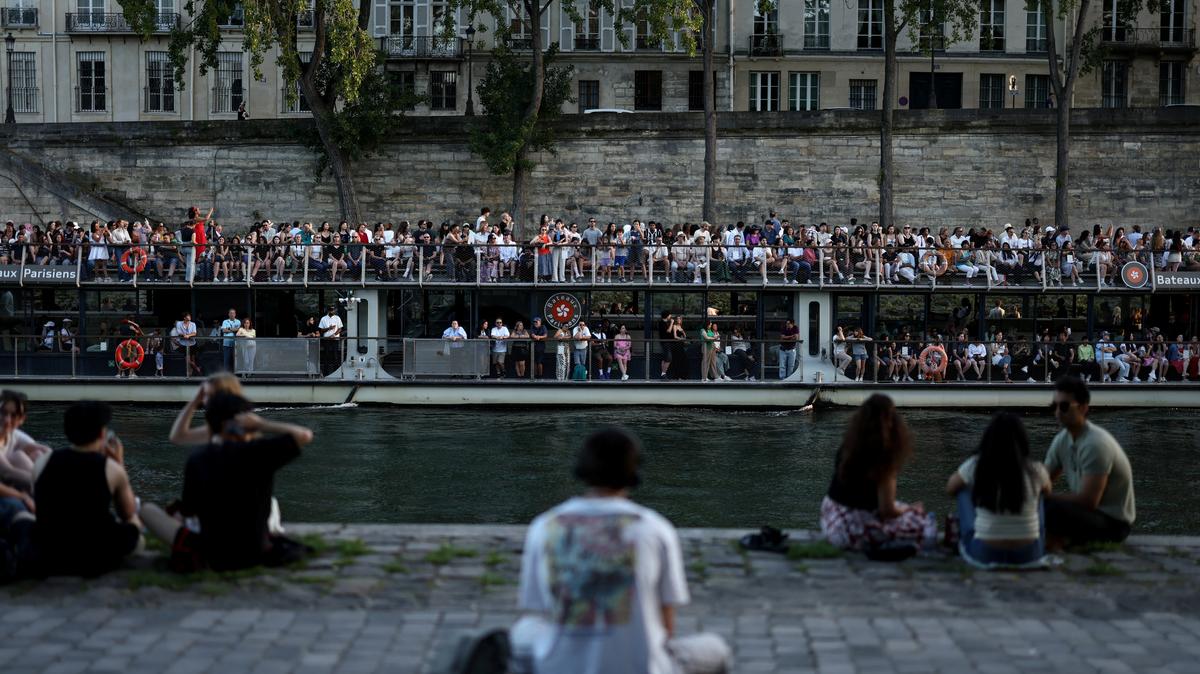 A boat passes people sitting on the banks of the Seine River, as temperatures reached up to 35 degrees during a period of hot weather in Paris, France, May 25, 2026. REUTERS/Tom Nicholson