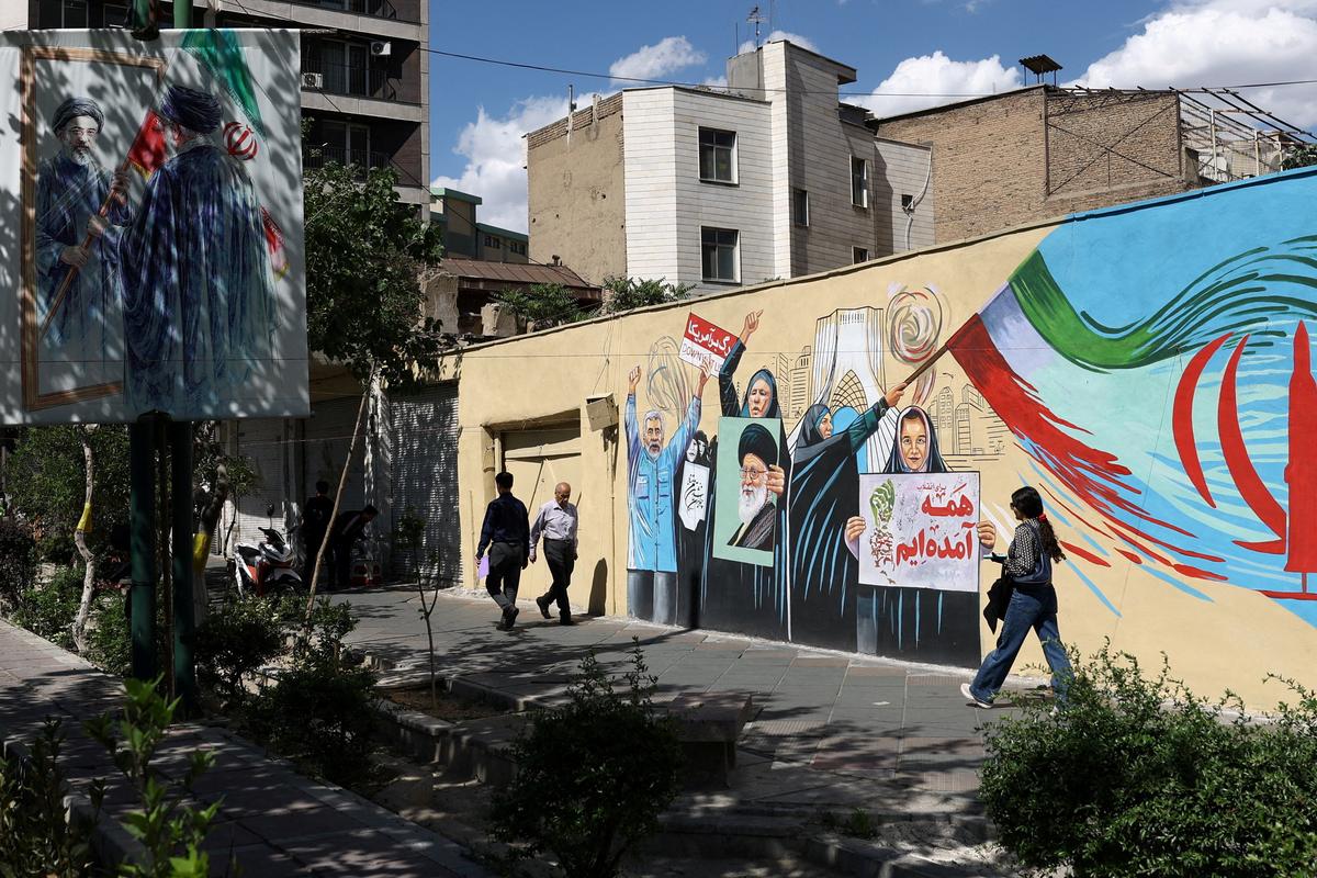People walk on a street near a mural featuring an image of the late Supreme Leader of Iran, Ayatollah Ali Khamenei, in Tehran, Iran, May 18, 2026. Majid Asgaripour/WANA (West Asia News Agency) via REUTERS