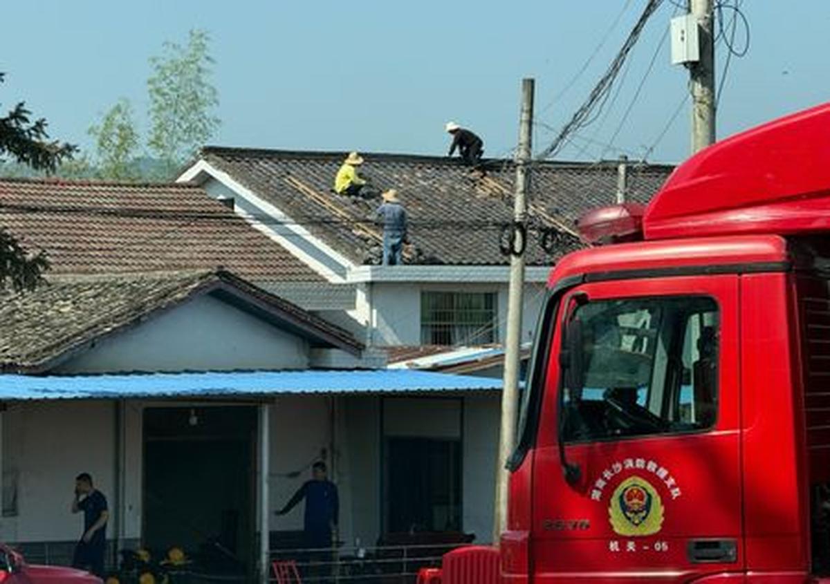 People repair a damaged roof next to a fire truck after a blast at a fireworks manufacturing factory in Liuyang, Hunan province, China, May 6, 2026. REUTERS/Maxim Shemetov